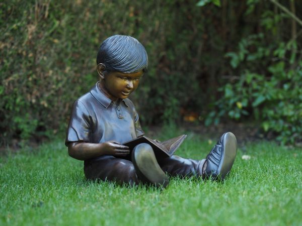 Bronzefigur sitzender Junge mit Buch