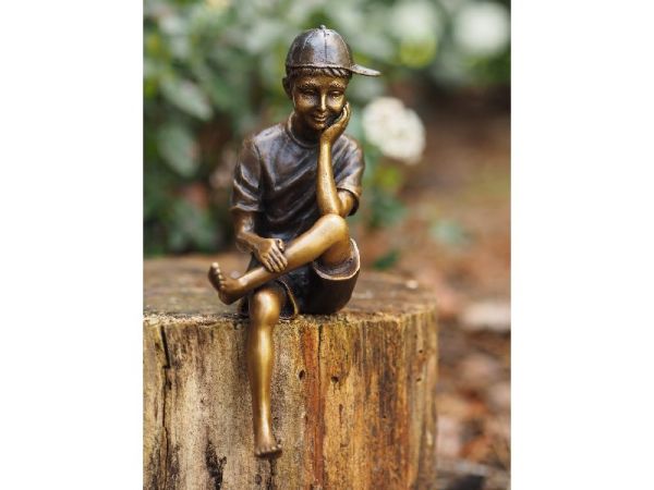 Bronzefigur sitzender Junge mit Mütze